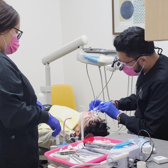 Un dentista y una asistente con uniforme negro de Soleil atendiendo a un paciente