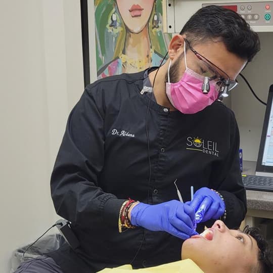 Dr. Aldana in black Soleil scrubs treating a patient