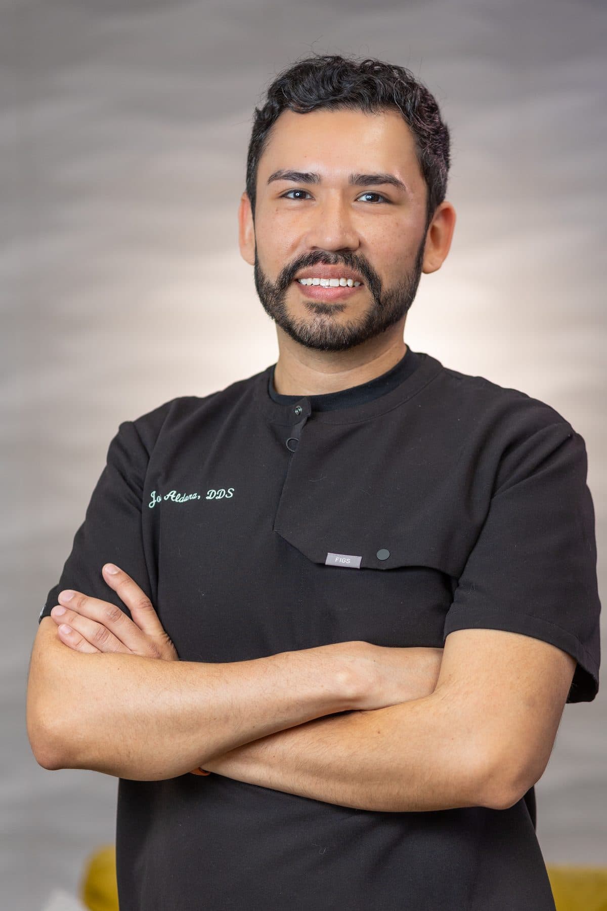 Dr. Jose Aldana with arms crossed in his black Soleil scrubs