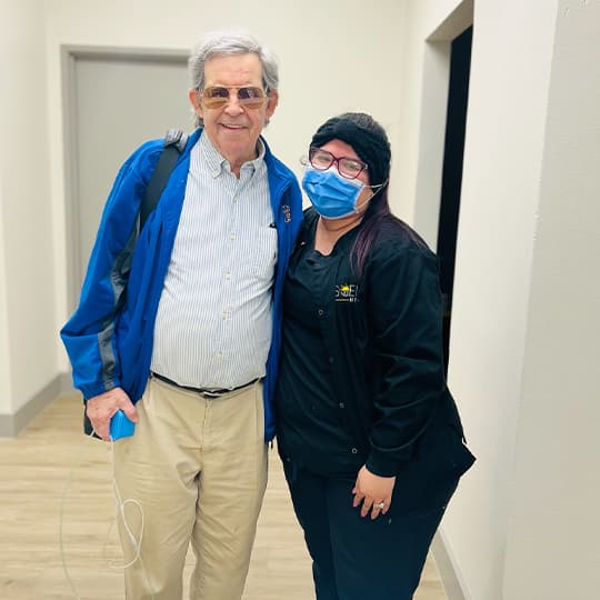 A smiling patient standing with a Soleil team member in the office hallway