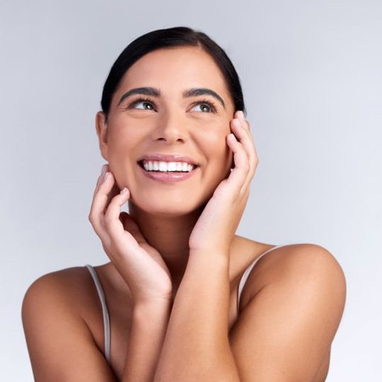 Smiling woman with beautiful skin pictured against neutral background