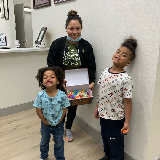 Two child patients and dentist smiling at front desk