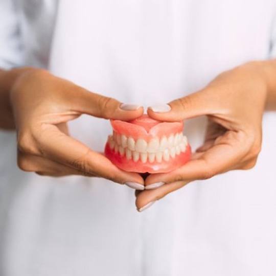 a closeup of a dentist holding dentures