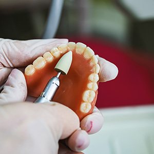 Dental technician filing a denture