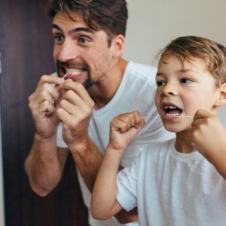 Father and child flossing to prevent dental emergencies