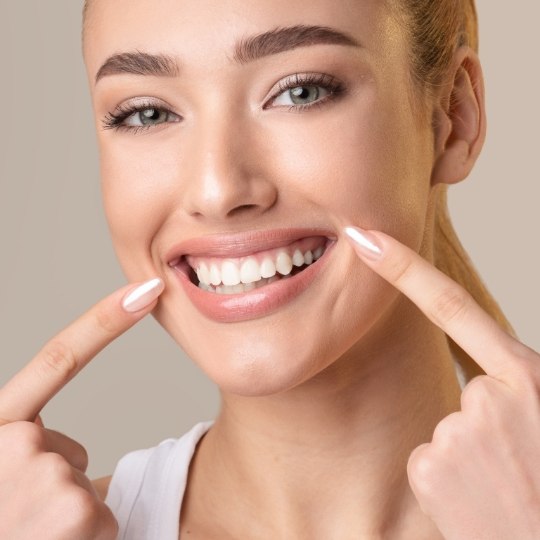 Woman pointing to healthy smile after periodontal disease treatment