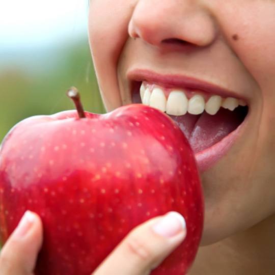 Closeup of patient with dental implants in Dallas eating an apple