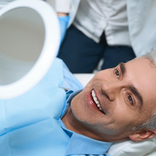 Man admiring his new smile after getting dental implants in Dallas