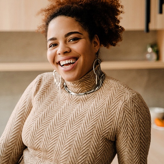 Woman with dental implants in Dallas, TX smiling in kitchen