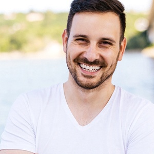 Man with dental implants in Dallas, TX smiling by lake