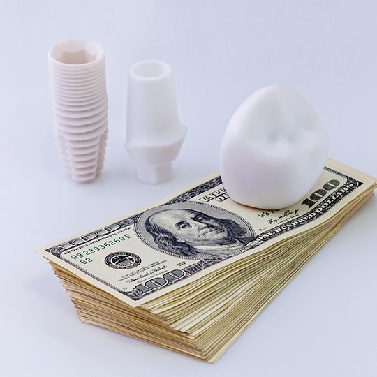 An implant sitting on a stack of cash, symbolizing the cost of dental implants in Dallas