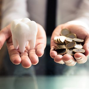 A fake tooth and coins that mark the cost of dental implants in Dallas