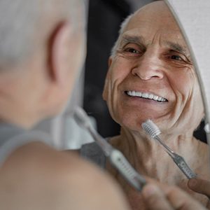 Man smiling while brushing his teeth