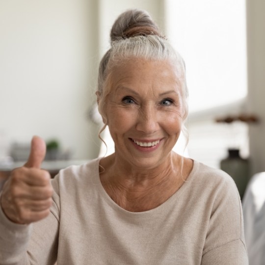 Woman giving thumbs up after visiting her dentist in Dallas Texas