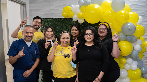 Soleil Dental team standing in Dallas dental office and holding up index fingers