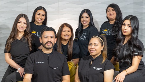 Soleil Dental team standing in Dallas dental office and holding up index fingers