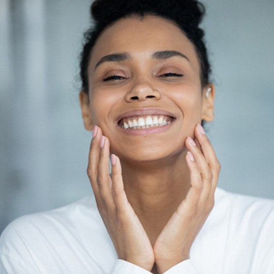 young woman touching her face and smiling