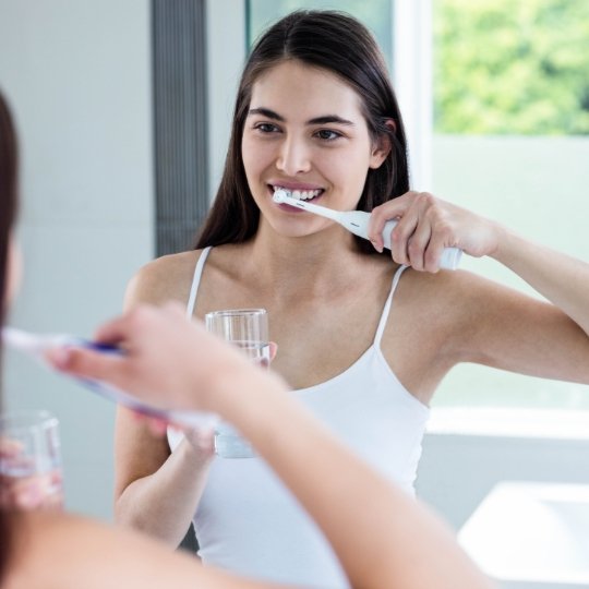 Woman brushing teeth before preventive dentistry visit