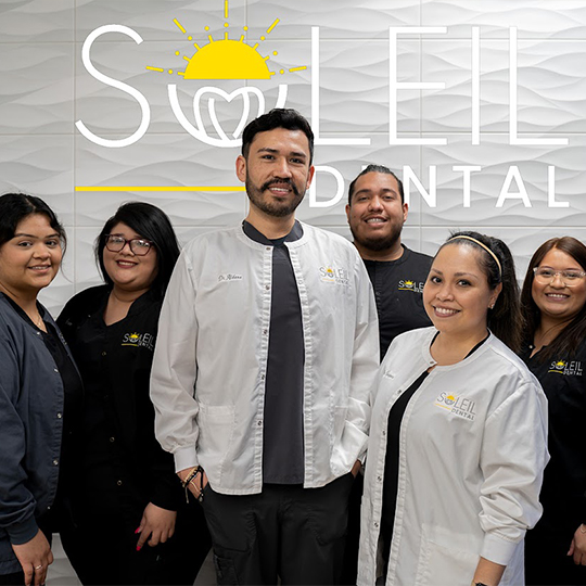 Soleil Dental team standing in front of practice logo