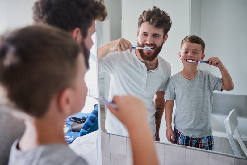 parent and child cleaning their teeth in Dallas