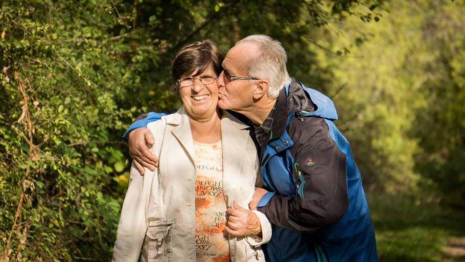 older person with dentures kissing partner on cheek 