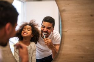 a daughter having fun brushing her teeth with her dad