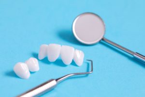 Veneers on a blue background next to dental instruments