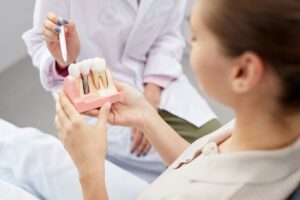 Doctor showing patient a model of a dental implant.