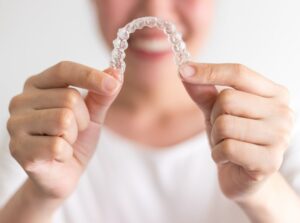 Person holding Invisalign in close-up in foreground.