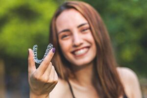 Woman holding out Invisalign clear aligner.