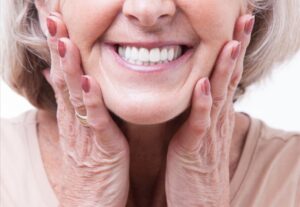 Older woman smiling and showing dentures.